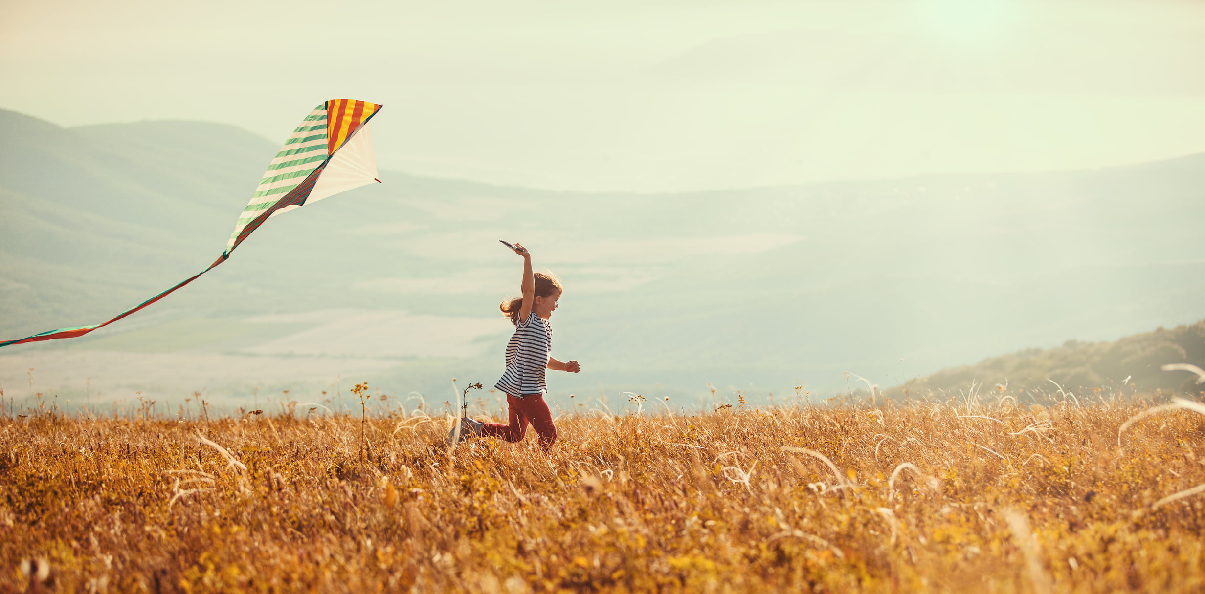 happy child girl running with kite at sunset outdoors
