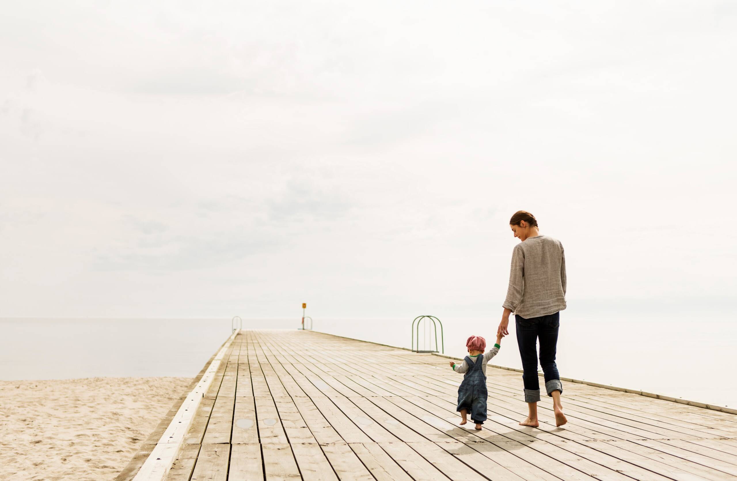 Barn och mamma håller varandras händer går på brygga